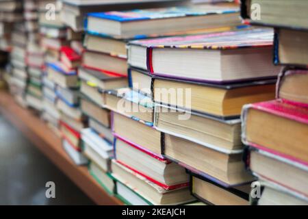 Alte gebrauchte Bücher stehen im Buchladen auf dem Tisch. Viele Bücher stapeln sich auf dem Bücherflohmarkt. Hintergrund... Stockfoto