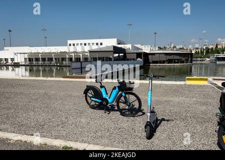 Elektrofahrräder und E-Scooter auf dem Pier geparkt Stockfoto
