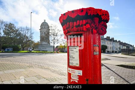 Brighton UK 11.. November 2022 - Am Waffenstillstandstag in Großbritannien Ist Eine gestrickte Mohnhülle (Yarn Bombing) auf dem Postkarton im Queens Park in Brighton erschienen. Der Waffenstillstand, eine Vereinbarung zur Beendigung der Kämpfe des Ersten Weltkriegs als Auftakt zu Friedensverhandlungen, begann am 11. November 1918 um 11am Uhr : Credit Simon Dack / Alamy Live News Stockfoto