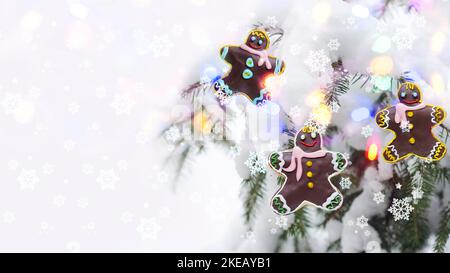 Weihnachtskonzept mit Lebkuchenmännern auf dem Hintergrund eines entkofften Weihnachtsbaums und Bokeh Stockfoto