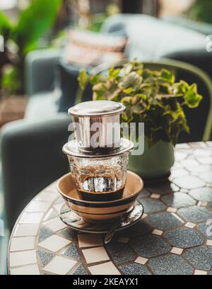 Vietnamesischen Kaffee mit Kondensmilch in Glas Tassen und traditionellen Metall Kaffeemaschine phin. Traditionelle Verfahren zur Herstellung von vietnamesischen Kaffee Stockfoto