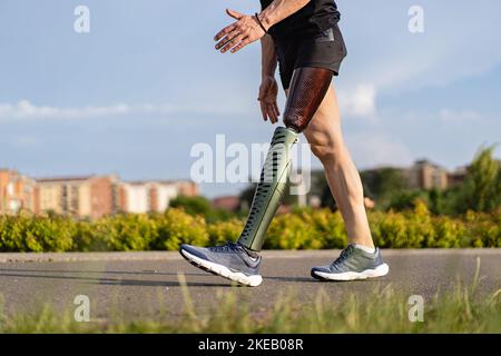 Low-Angle-Ansicht auf behinderte junge Mann mit prothetischen Bein zu Fuß entlang der A-Weg im Park - Gesundheitsversorgung und Menschen Lifestyle-Konzept Stockfoto