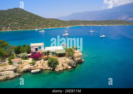 Einsame Villa an der Küste des Mittelmeers in der Türkei, Kas. Luftaufnahme von türkisfarbenem Wasser, Bergen und Yachten Stockfoto