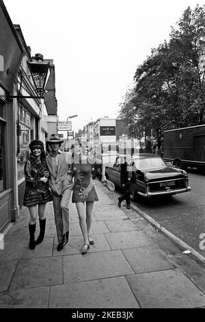 London in den 1960er. Ulla Larsson und Birgitta Bjerke an der 251 Kings Road vor den Antiquitätenmarktständen. Sie tragen die typische 1960er-Mode ihres eigenen Designs. Die Identität des Mannes ist unbekannt. Ein Bild, das während der Zeit der Swinging Sixties aufgenommen wurde, einer von der Jugend angetriebenen kulturellen Revolution in Großbritannien Mitte bis Ende der 1960er Jahre. Beachten Sie die typische handgemusterte Kleidung. London England, 1967. Oktober. Stockfoto