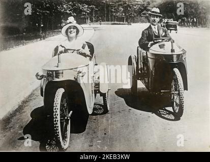 Elektrofahrzeuge im Jahr 1930s. Jeny Golden ist der Star der Show im Theater Casino de Paris. Sie ist abgebildet, wie sie in einem ähnlichen Modell ein elektrisches dreieckiger Fahrzeug neben einem Gentleman fährt. Dies geschah in einer Pariser Straße im Jahre 1930s. Stockfoto