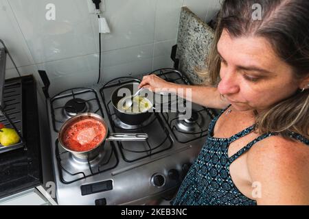 Junge Frau bereitet Käsekuchen in der Küche mit verschiedenen Zutaten zu. Familiengastronomie. Salvador, Bahia, Brasilien Stockfoto