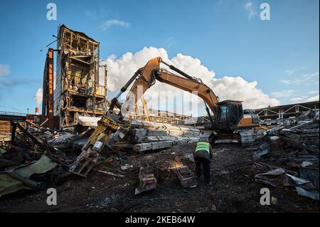 Ein Mitarbeiter im Helm schneidet alte Metallbalken für das Recycling vor Ort Stockfoto