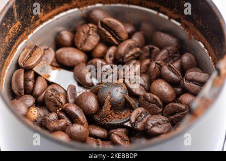 Weicher Fokus auf geröstete Kaffeebohnen in einer elektrischen Kaffeemühle. Fokus im Vordergrund. Stockfoto