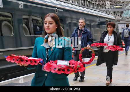 London, Großbritannien, 11.. November 2022. Die Mitarbeiter der Station bringen Mohnkränze, wenn sie in Paddington ankommen. Kriegsveteranen, Mitarbeiter der Great Western Railway (GWR) und Mitglieder der Öffentlichkeit versammelten sich in der Paddington Station zu einem jährlichen Waffenstillstandstag-Gedenkgottesdienst. Kränze kamen heute Morgen auf Zugverbindungen aus zahlreichen Städten entlang des GWR-Netzes an, als sie von Veteranen oder Beamten in der Operation Third Poppies to Paddington an Bord gebracht wurden. Kredit: Elfte Stunde Fotografie/Alamy Live Nachrichten Stockfoto