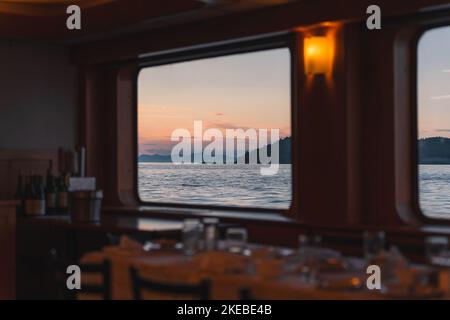 Eine wunderschöne Aufnahme eines ruhigen Meeres bei Sonnenuntergang von einem Kreuzfahrtfenster in Alaska Stockfoto