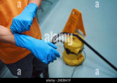 Professioneller Reiniger, der während der Arbeit geeignete Handschuhe verwendet Stockfoto