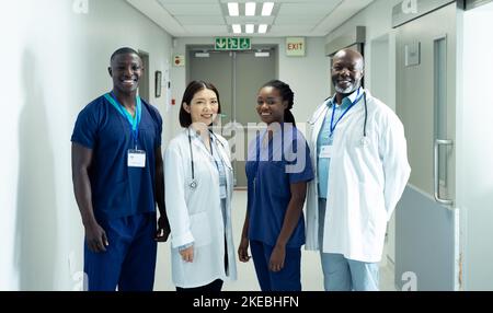 Porträt einer vielfältigen Gruppe von vier Ärzten und Krankenhauspersonal, die im Krankenhauskorridor lächeln Stockfoto