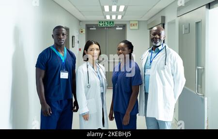 Portrait einer vielfältigen Gruppe von vier Ärzten und medizinischem Personal im Krankenhauskorridor Stockfoto