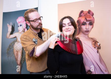 Birmingham, Großbritannien. 11.. November 2022. Die Kunstverwalterin Simona Matuozzo probiert ein Halsstück namens Pagoda II des Künstlers Dauvit Alexander. Die Arbeit ist Teil einer Ausstellung "Queer Metals" im Midlands Arts Centre, Birmingham, vom 12.. Bis 19. November. Die 8 Künstler der Schau beschäftigen sich mit der Metallverarbeitung und der Vielfältigkeit von Queerness. Kredit: Peter Lopeman/Alamy Live Nachrichten Stockfoto