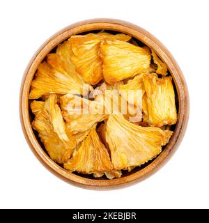 Dehydrierte Ananasstücke in einer Holzschüssel. Getrocknete Stücke von Ananas comosus, die als Snack, für Müsli oder Wandermischungen verwendet werden. Stockfoto