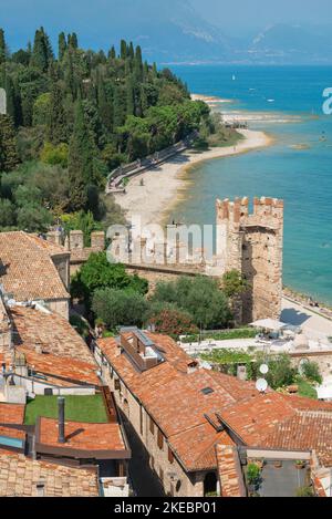 Sirmione Strand, Blick über die malerischen Dächer von Sirmione zum Strand am Ostufer der Halbinsel Sirmione, Gardasee, Lombardei Italien Stockfoto