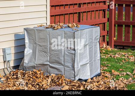 Haus-Klimaanlage mit Schutzabdeckung während der Herbstsaison. Konzept der häuslichen Klimaanlage, hlk, Reparatur, Service, winterfest und Wartung Stockfoto