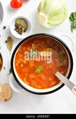 Kohlsuppe in Brühe Topf auf weißem Stein Hintergrund. Draufsicht, flach liegend Stockfoto
