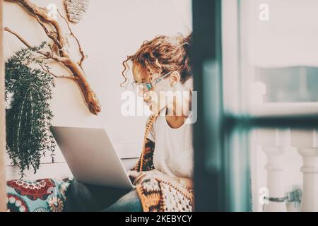 Eine vielbeschäftigte Frau, die zu Hause auf der Terrasse sitzt und ihren Laptop benutzt. Konzept der modernen weiblichen Menschen und drahtlose Computer-Technologie-Verbindung. Lady genießt das Surfen im Internet für Job Vergnügen Stockfoto