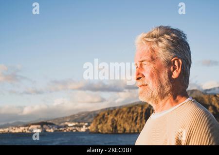 Nahaufnahme und Porträt eines traurigen und nachdenklichen Mannes, der das Meer am Strand betrachtet - verärgert Menschen Lifestyle-Konzept Stockfoto