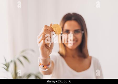 Teenager hält eine virtuelle goldene Bitcoin mit seiner Hand zeigt es der Kamera lächelnd und Spaß haben. Stockfoto