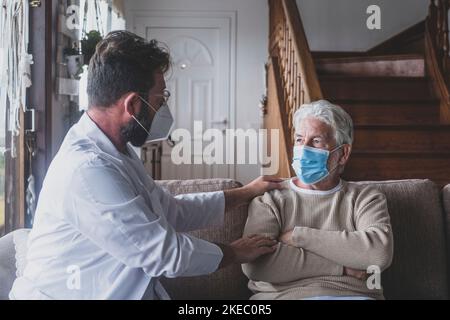 Männliche professionelle Arzt Beratung Senior Patient während der medizinischen Versorgung Besuch trägt Masken. Ein junger Arzt und ein alter älterer Herr, der auf dem Sofa sitzt und medizinische Hilfe leistet. Ältere Menschen in der häuslichen Pflege. Covid- und Coronavirus-positiver Test Stockfoto