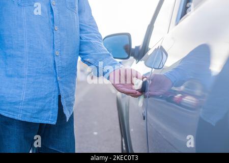 Nahaufnahme und Porträt eines alten Mannes, der die Tür seines neuen Autos öffnet und den Luxus genießt. Zufriedenes Kundenkonzept. Stockfoto