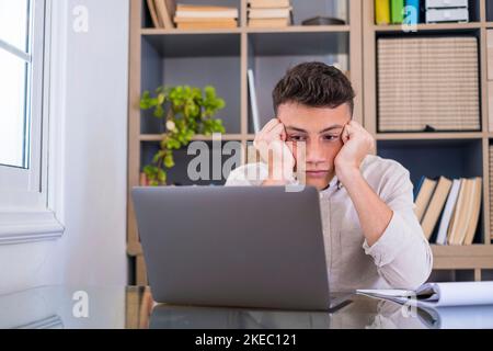 Müde männliche Student oder Arbeiter sitzen zu Hause Schreibtisch Blick in der Ferne Schlafentzug, faul Millennial Mann abgelenkt von der Arbeit fühlen faul Mangel an Motivation, denken an langweilige monotone Arbeit Stockfoto