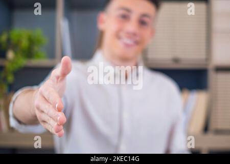 Ein lächelnder Geschäftsmann mit einem Kopfbild, der die Hand zum Händeschütteln an der Kamera streckte, ein freundlicher Manager begrüßt den Kandidaten im Interview, bietet einen Deal an, begrüßt den Kunden beim Meeting Stockfoto