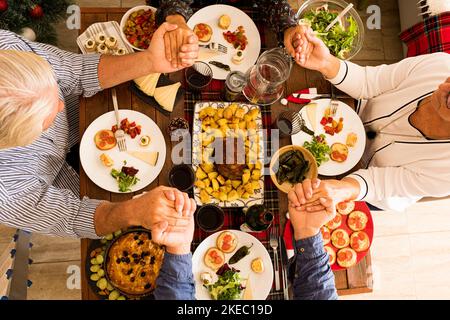 Oben und oben Blick auf einen großen Holztisch voll Von Lebensmitteln wie Huhn und Gruppe von Menschen essen und Essen aus der Mitte des Tisches nehmen die weihnachten Tag Stockfoto