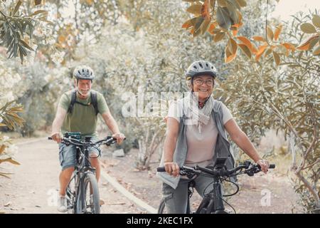 Zwei glückliche alte ältere Menschen genießen und gemeinsam Fahrrad fahren, um im Freien fit und gesund zu sein. Aktive Senioren, die Spaß beim Training in der Natur haben. Stockfoto