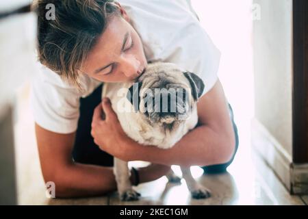 Paar Teenager und niedlichen weißen Mops - Liebe und Zuneigung von zwei besten Fritten zu Hause - lieben die Tiere Stockfoto