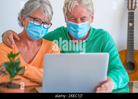 Zwei glückliche Senioren und ältere Menschen, die zu Hause im Lockdown-Lebensstil mit jemandem in Videoanrufen sprechen Stockfoto