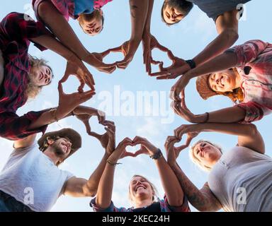 Eine Gruppe von sieben Menschen zusammen, die mit Fingern und Händen ein Herz machen - Menschen in einer Krippe, die Spaß haben und spielen - Grundansicht Stockfoto