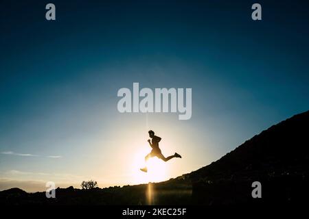 Ein Teenager läuft allein bei Sonnenuntergang - Silhouette von Mann tun Joggen -gesunde und Fitness Lifestyle-Konzept Stockfoto