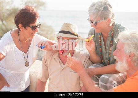 Gruppe von Menschen, die Spaß zusammen feiern etwas passiert - Vier Senioren lächeln und lachen am Strand Stockfoto