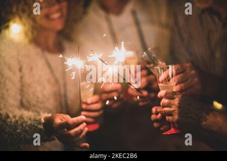 Gruppe von vier Personen, die Spaß haben und gerne eine Brille halten Champagner und Wunderkerzen feiern gemeinsam das glückliche neue Jahr Stockfoto