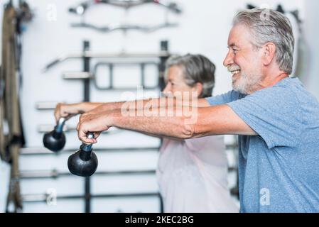 Zwei glückliche und reife aktive ältere und gesunde Menschen tun Gemeinsam trainieren Sie im Fitnessstudio mit einer kleinen Hantel - Frau und Mann Rentner Spaß haben Stockfoto