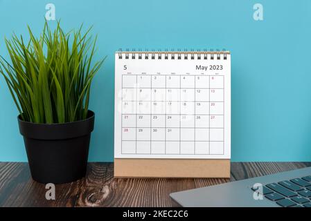 Mai 2023 Tischkalender mit grüner Topfpflanze und Laptop Stockfoto