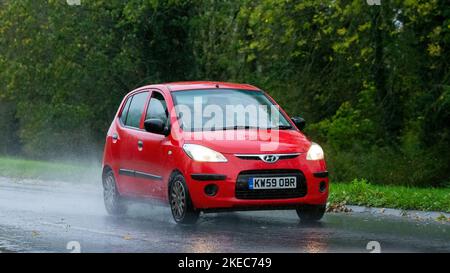 2010 rotes Hyundai i10 Auto, das im Regen auf nasser Straße fährt Stockfoto