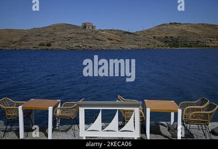 Seascape mit szenischem Blick auf ein traditionelles griechisches Café Rattan Möbel an der Küste von Vourkari in Kea Insel, Kykladen Griechenland. Stockfoto