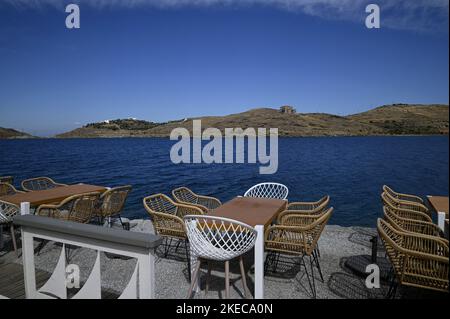 Seascape mit szenischem Blick auf ein traditionelles griechisches Café Rattan Möbel an der Küste von Vourkari in Kea Insel, Kykladen Griechenland. Stockfoto