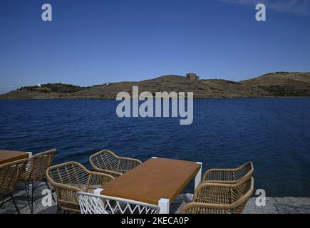 Seascape mit szenischem Blick auf ein traditionelles griechisches Café Rattan Möbel an der Küste von Vourkari in Kea Insel, Kykladen Griechenland. Stockfoto