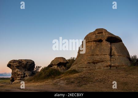 Heilige Felsen, Berge in der Form eines Kopfes, der von der untergehenden Sonne beleuchtet wird. Rock Bergklippe über Sonnenuntergang Himmel Hintergrund Ein Ort der Macht. Ein Ort Stockfoto