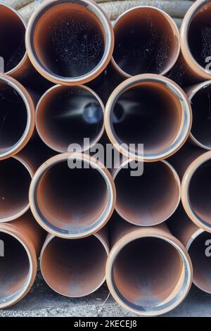Eine vertikale Aufnahme eines Stapels aus rot geschweißten Stahlrohren Stockfoto