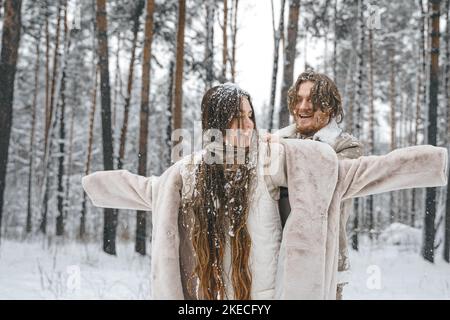 Romantische Schnee Liebe Story.Young paar Kerl Mädchen liegen, spielen im verschneiten Winterwald mit trees.Walking, Spaß haben, lachen in stilvollen warmen Kleidung, Stockfoto