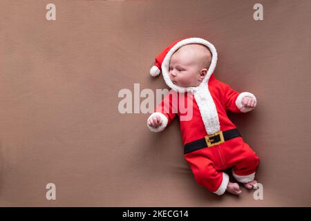 Neugeborenes Mädchen in weihnachtsmann Kostüm gähnend müde gekleidet. Stockfoto