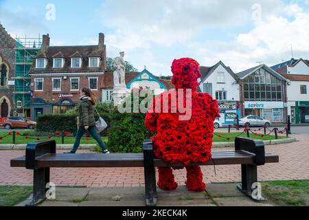 Chesham, Buckinghamshire. VEREINIGTES KÖNIGREICH. 11. November 2022. Eine auffällige Figur zum Gedenktag, in der ein Mann mit roten Mohnblumen auf einem Sitz in Chensham neben dem Kriegsdenkmal sitzt und eine weiße Taube in der Hand hält. Quelle: Maureen McLean/Alamy Live News Stockfoto