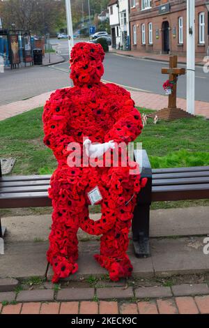 Chesham, Buckinghamshire. VEREINIGTES KÖNIGREICH. 11. November 2022. Eine auffällige Figur zum Gedenktag, in der ein Mann mit roten Mohnblumen auf einem Sitz in Chensham neben dem Kriegsdenkmal sitzt und eine weiße Taube in der Hand hält. Quelle: Maureen McLean/Alamy Live News Stockfoto