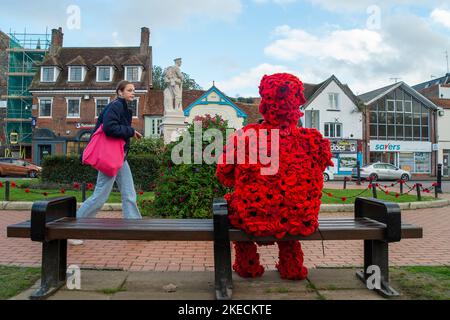 Chesham, Buckinghamshire. VEREINIGTES KÖNIGREICH. 11. November 2022. Eine auffällige Figur zum Gedenktag, in der ein Mann mit roten Mohnblumen auf einem Sitz in Chensham neben dem Kriegsdenkmal sitzt und eine weiße Taube in der Hand hält. Quelle: Maureen McLean/Alamy Live News Stockfoto